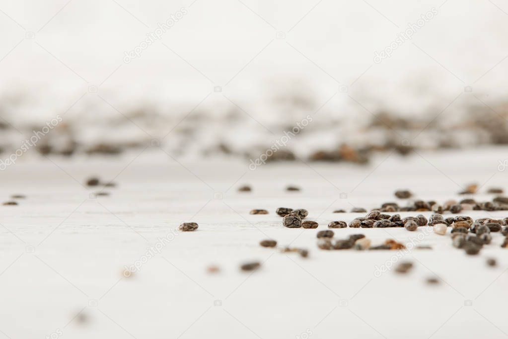 selective focus of chia seeds on white wooden tabletop