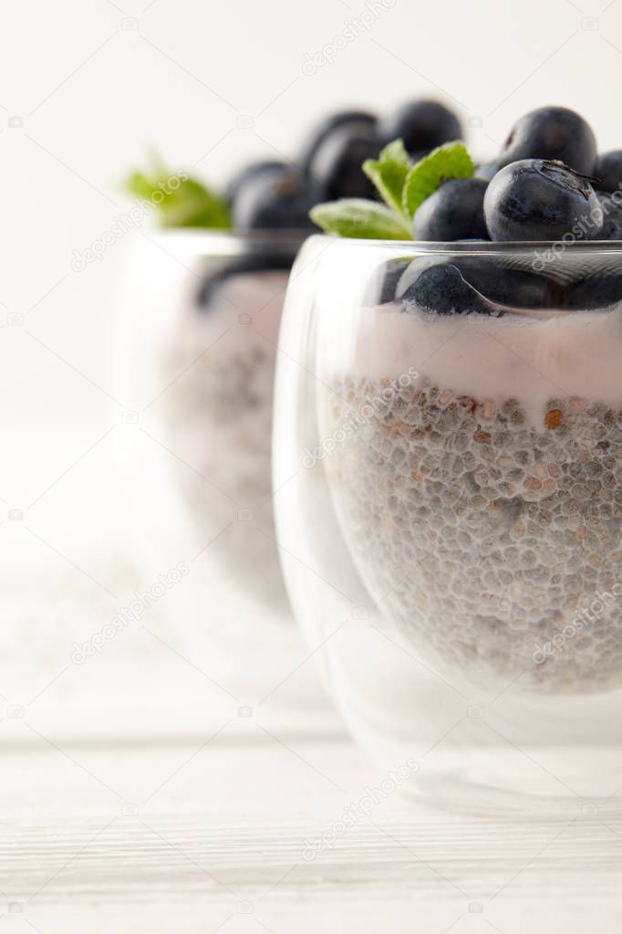 selective focus of chia puddings with fresh blueberries and mint on surface