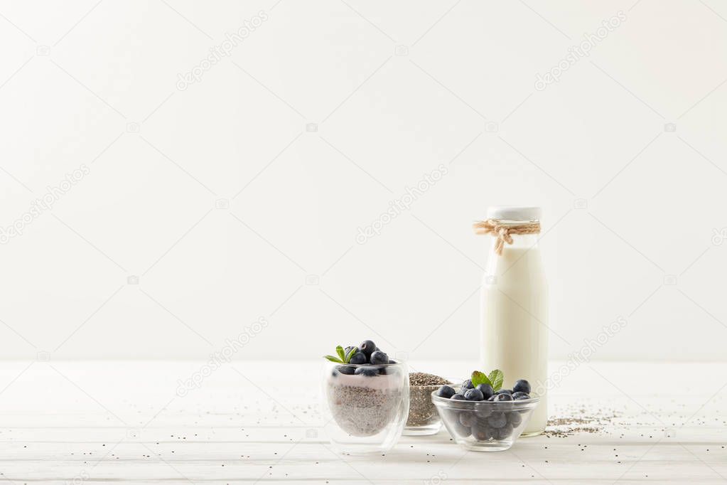 close up view of chia pudding and ingredients on white wooden surface
