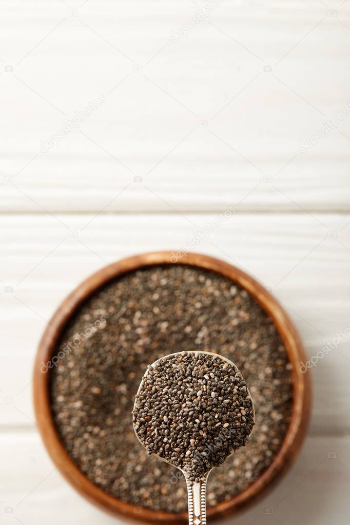 selective focus of chia seeds and spoon in wooden bowl on white surface