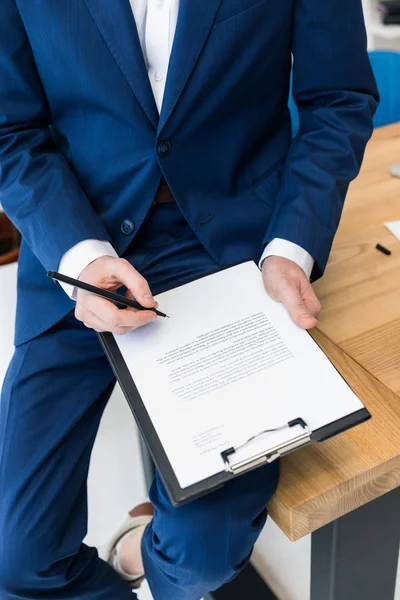 Обрезанный снимок бизнесмена с блокнотом и ручкой в руках на рабочем месте в офисе — стоковое фото