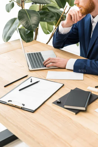 Обрізаний знімок бізнесмена, який працює на ноутбуці на робочому місці в офісі — стокове фото