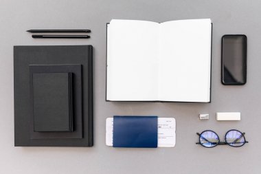 siyah notebook, smartphone, boş açılan defter, pasaport ve bilet işyerinde görücü usulü yığın Üstten Görünüm
