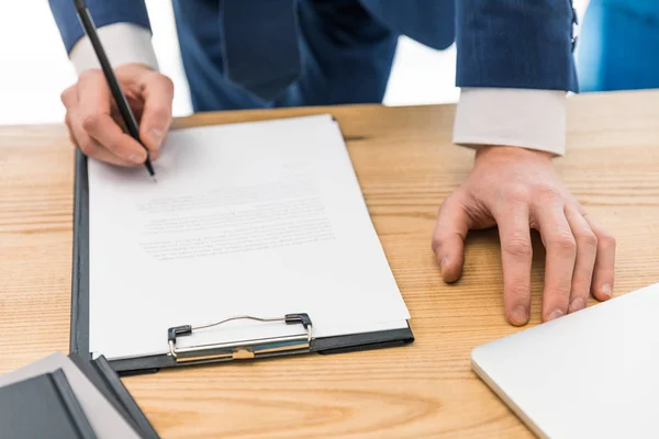 Gedeeltelijke weergave van zakenman ondertekenen papieren op werkplek — Stockfoto