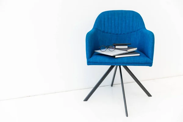 Close up view of laptop, black notebook and eyeglass on blue chair on white backdrop — Stok Foto