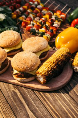 Burgers and corn cooked outdoors on grill clipart