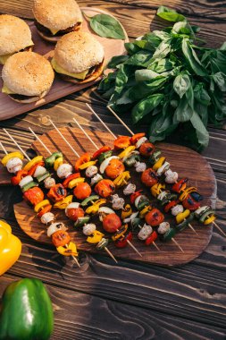 Vegetables on skewers and hamburgers cooked outdoors on grill clipart