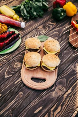 Cut vegetables and burgers grilled for outdoors barbecue clipart