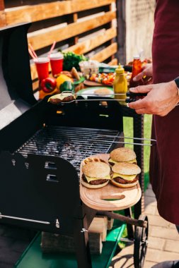 Adam açık havada ateş burgers için et ızgara