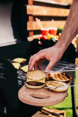 Hamburger eti ayarlama çörek adam açık havada ızgarada pişmiş
