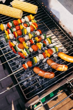 Sausages grilled for outdoors barbecue with vegetables on skewers clipart