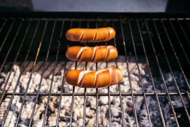 Three sausages grilled for outdoors barbecue over fire clipart