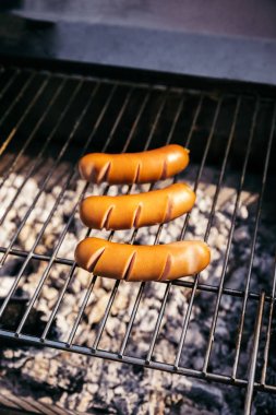 Hot sausages cooked outdoors on grill over coals clipart