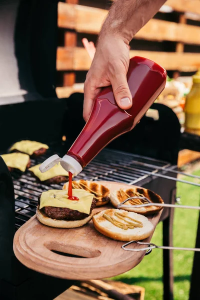 Man Toevoegen Ketchup Aan Hamburgers Gekookt Buitenshuis Grill — Stockfoto