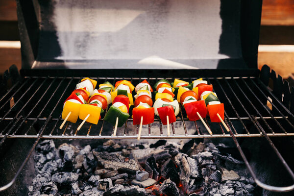 Vegetables on wooden skewers cooked outdoors on grill over fire