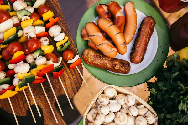 Table with sausages and vegetables with mushrooms grilled for outdoors barbecue