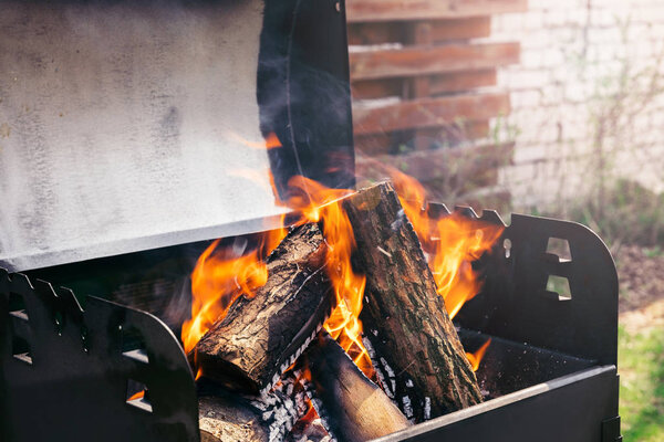 Fire over wooden logs in outdoors bbq