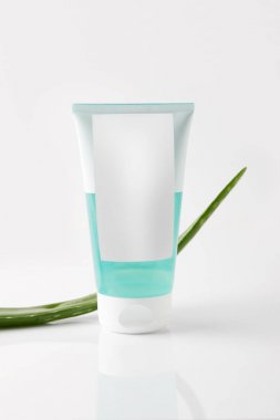 closeup view of cream tube and aloe vera leaf on white surface clipart