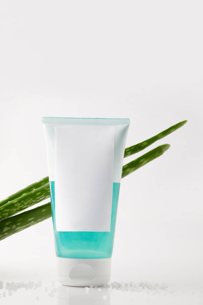 closeup shot of aloe vera leaves and cream tube on surface with salt 