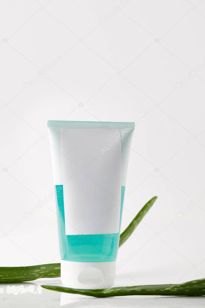 closeup view of cream tube and aloe vera leaves isolated on white background 