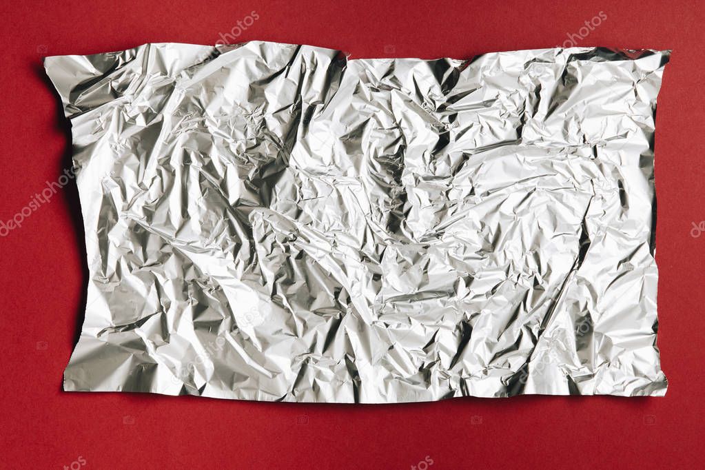 close-up view of empty crumpled foil texture on dark red background