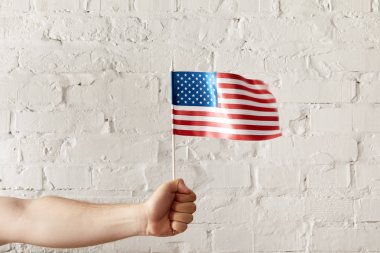 Amerikan bayrak direğine beyaz tuğla duvara tutan adam resmini kırpılmış 