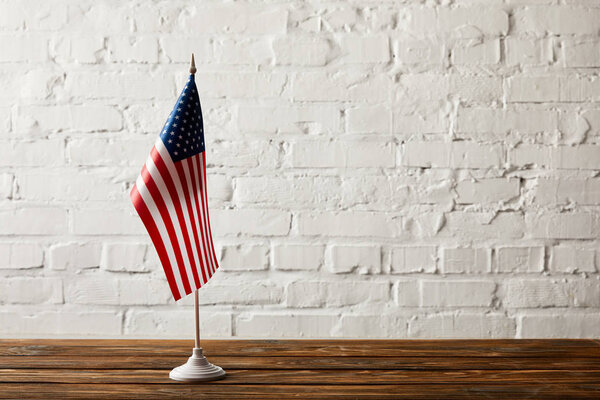 united states of america flagpole on wooden surface against brick wall 