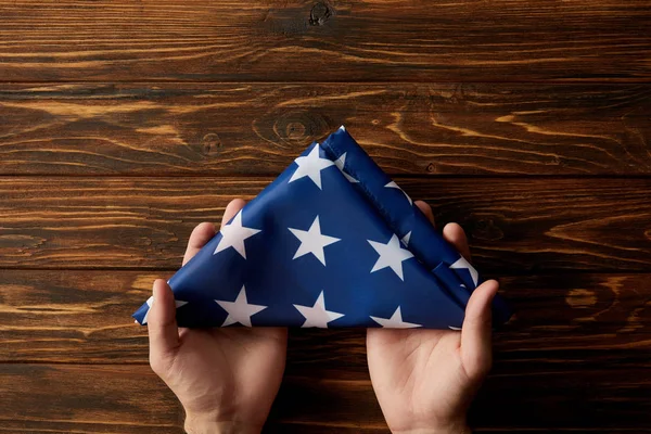 Corte Tiro Homem Segurando Dobrado Estados Unidos Bandeira Fundo Madeira — Fotografia de Stock