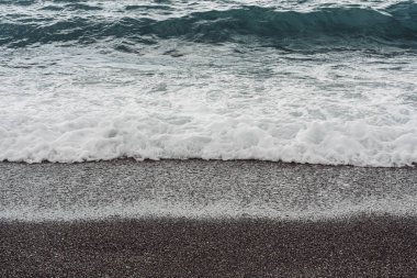 Deniz dalgaları yazın kumlu sahillere vurur. 