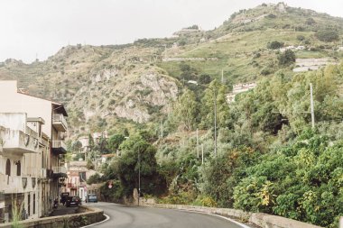 buildings near road and hills with trees in italy  clipart