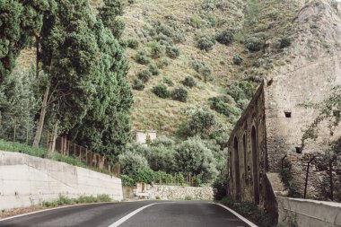 Yol kenarındaki eski bina ve İtalya 'daki yeşil ağaçlar. 