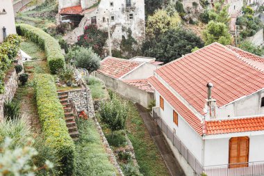 Sicilya 'daki ağaçların ve bitkilerin yakınındaki tepelerdeki küçük evlerin seçici odağı 