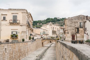 Scicli, İtalya - 3 Ekim 2019: Eski kilisenin ve Sicli 'deki binaların yakınında kaldırım taşları olan cadde 