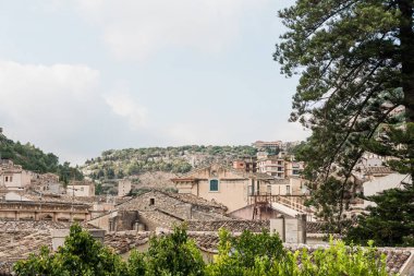 Modica, İtalya 'da yeşil bitkilerin ve ağaçların yanındaki küçük evler 
