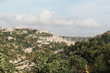 Ragusa, İtalya 'daki eski evlerin ve ağaçların çatılarında güneş ışığı. 