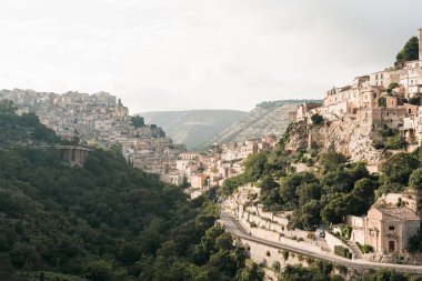 Ragusa, İtalya 'da küçük evler ve yol kenarındaki ağaçların üzerindeki güneş ışığı. 