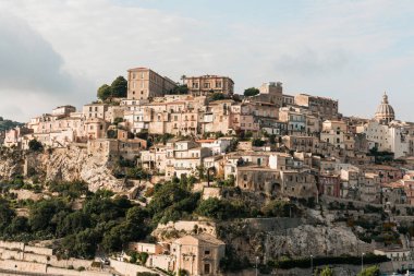 Ragusa, İtalya 'da küçük evlerin yakınındaki ağaçlarda güneş ışığı 