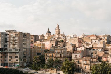 Catania, İtalya - 3 Ekim 2019 Saint Agatha Katedrali 'nin saat kulesi İtalya' da ağaçların yanındaki küçük evlerin yanında. 