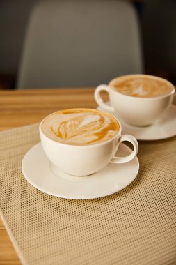 selective focus of cappuccino in white cups on table  clipart