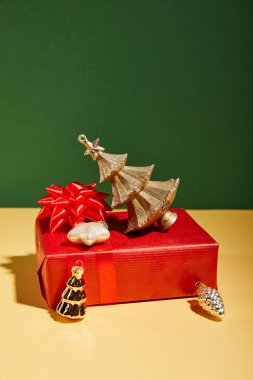 Sarı ve yeşil arka planda kırmızı hediye kutuları ve altın Noel süsü