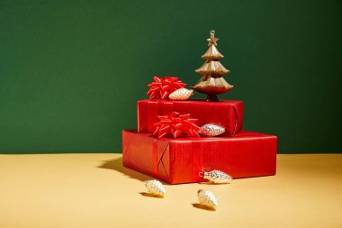 Sarı ve yeşil arka planda kırmızı hediye kutuları ve altın Noel süsü