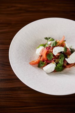 Tahta masada beyaz tabakta servis edilen peynirli lezzetli restoran salatası.