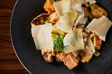 Tahta masada servis edilen parmesan dilimli lezzetli Sezar salatası.