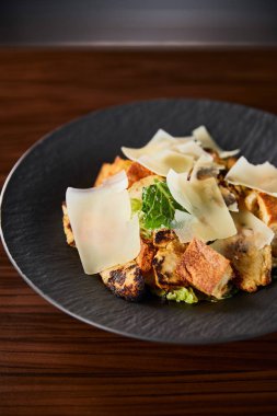 Tahta masada servis edilen parmesan dilimli lezzetli Sezar salatası.