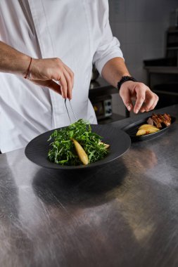 Mutfakta roka, et ve patates ile aşçı yemeklerinin kısmi manzarası.