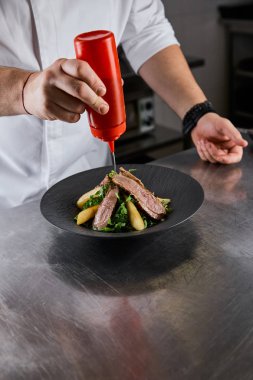 Yemeklere roka sosu, et ve patates karıştırılmış aşçı manzarası.