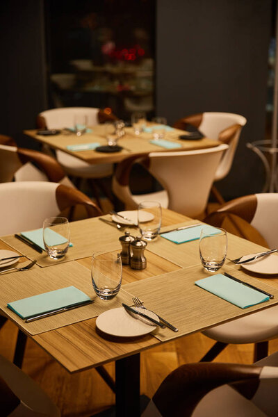 selective focus of glasses near plates and cutlery on wooden tables