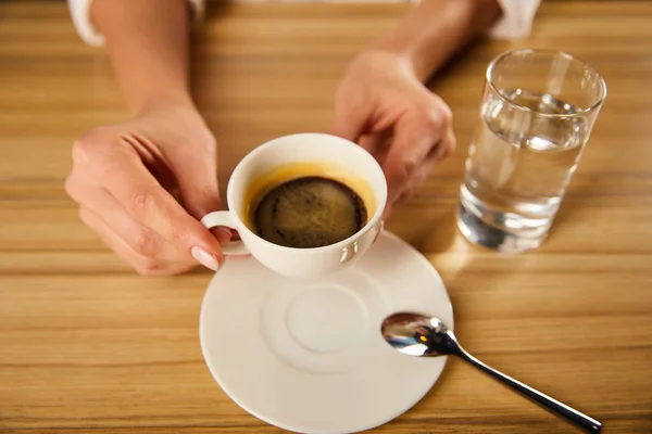 Szelektív Fókusz Kezében Csésze Kávét Pohár Víz Mellett Kávézóban — Stock Fotó