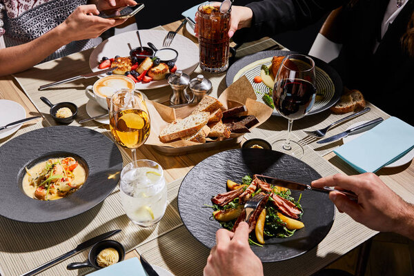 cropped view of people eating delicious food in restaurant 