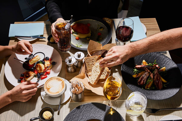 обрезанный вид людей, питающихся вкусной едой в ресторане
 